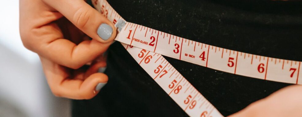pessoa com fita métrica medindo cintura
